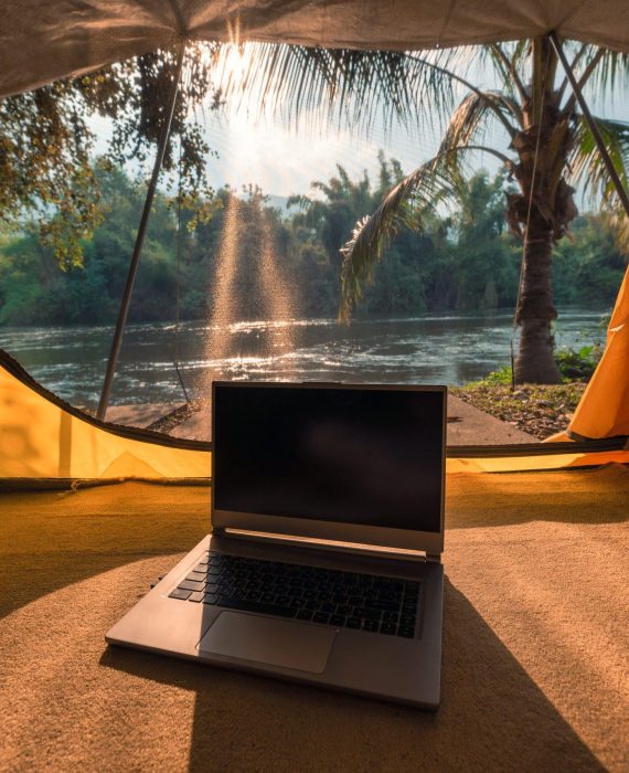 Modern laptop open and put down inside a camping tent in natural park at sunset